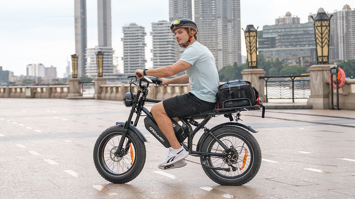 Rider on a HappyRun G70 electric delivery bike with a rear cargo bag along a city waterfront